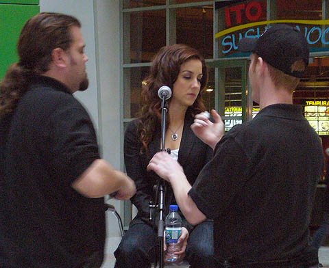 Two guys in black T-shirts seem to tend to Erin as she turns to the side with eyes closed