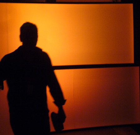 Man silhouetted against glowing orange scrims