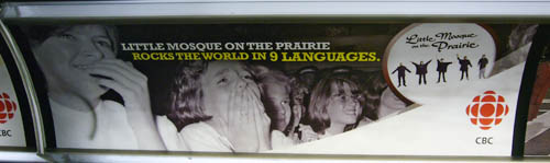Subway ad shows thrilled teenage girls (as at a Beatles concert) and the headline LITTLE MOSQUE ON THE PRAIRIE ROCKS THE WORLD IN 9 LANGUAGES