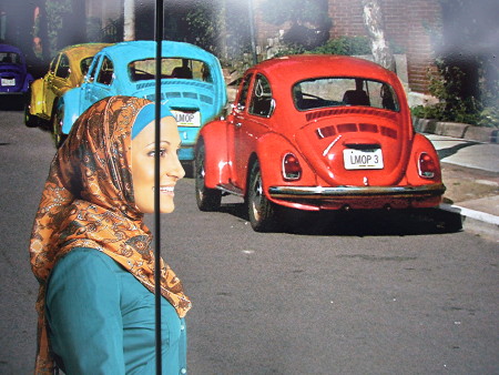 Close-up of photo of Rayyan from ‘Little Mosque’ crossing a street where two old Beetles are parked
