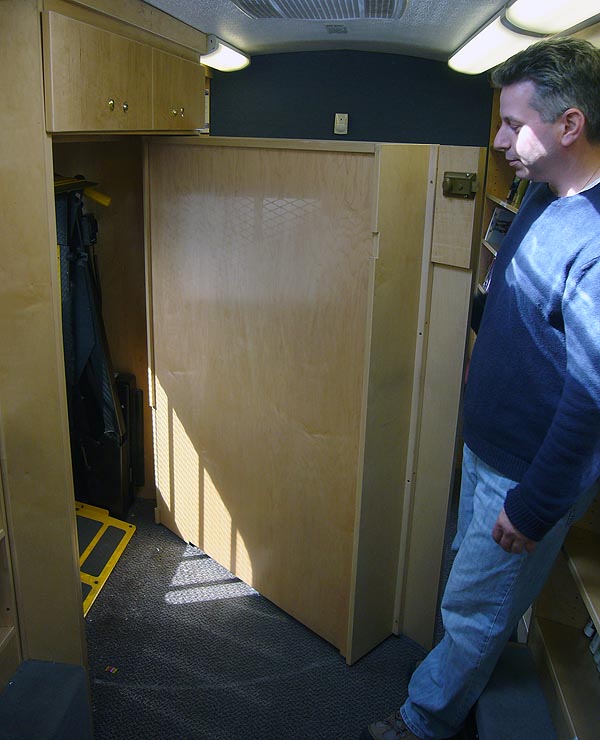 Man pulls open wall shelves to reveal a recess with a yellow lift inside