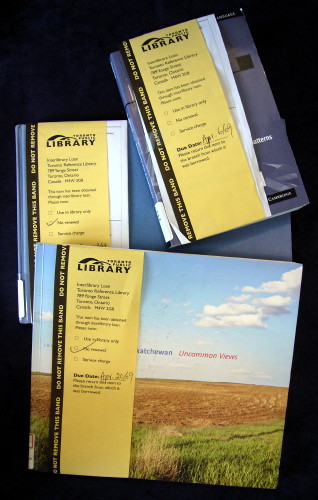 Three books with yellow interloan bands running down the covers