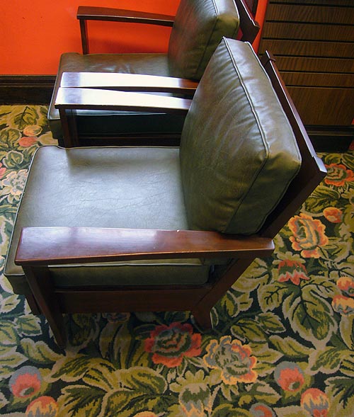Green leather easy chairs on floral carpeting