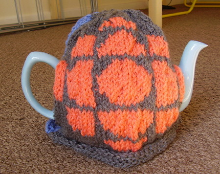Tea cozy has knit pattern of the CBC exploding pizza