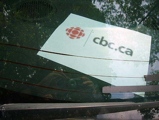 Blurry printout on dashboard under windshield shows pixelated CBC logo and cbc.ca