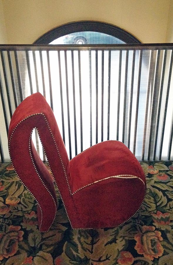 Pinkish, curvaceous chair with curved back like a clothespin