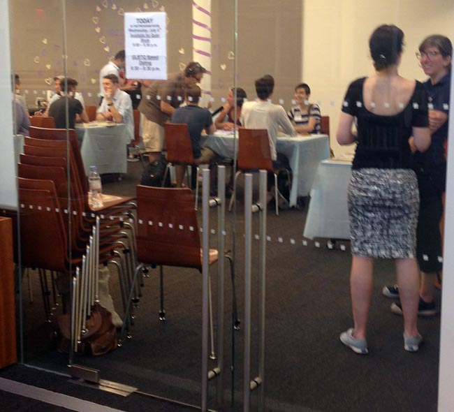 People seated across from one another at tables in activity room