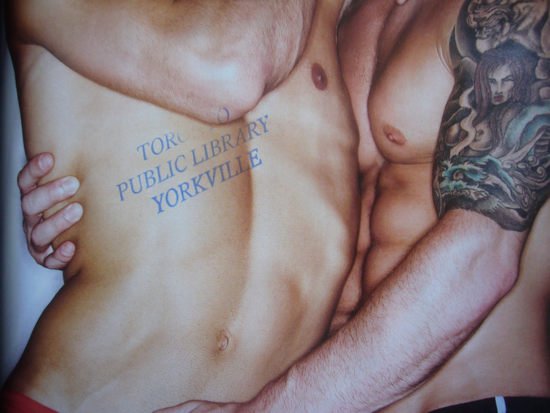 Library stamp on spread showing two shirtless guys hugging