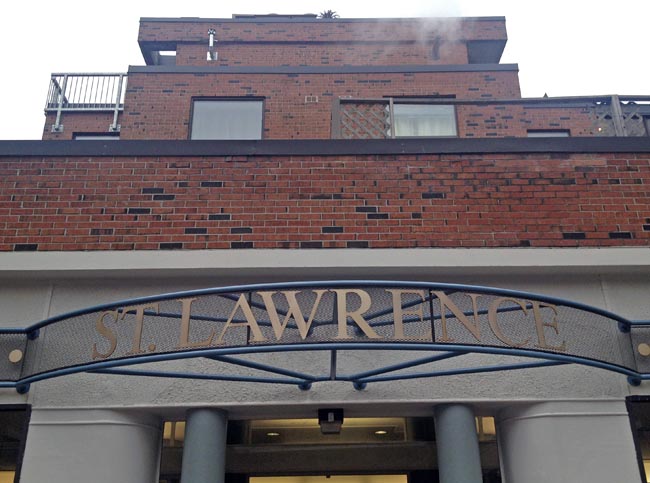 Brass ST. LAWRENCE nameplate in a semicircle projecting from brick building