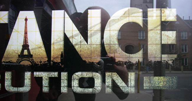 Fraction of sign shows ANCE UTION with scenes of Paris inside the first word