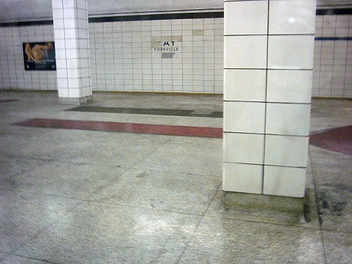 Filthy, decrepit, white-tiled subway station labelled AY YORKVILLE on far wall