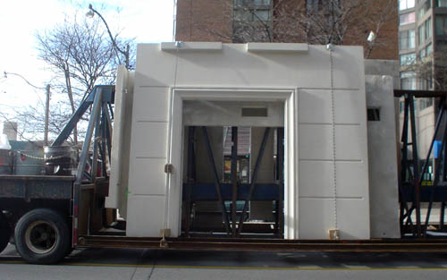 Low-riding steel transport trailer carries giant white square arches
