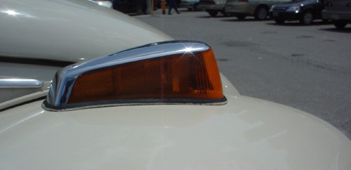 Red turn signal, shaped like a wedge with blunt corners and its point at the rear, sits atop a white rounded fender