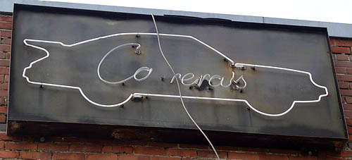 White neon sign on black background shows car outline with large rear spoiler and the name Ca rera’s