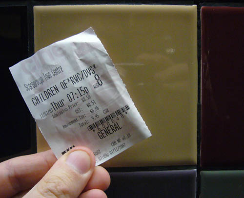Fingers hold up ticket stub labelled CHILDREN OF*RWC/DVS* against a tiled wall