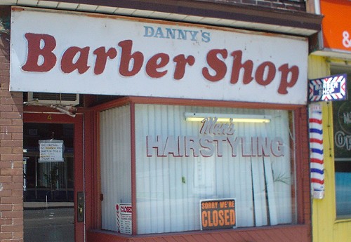 Sign over Men’s HAIRSTYLING place reads DANNY’s Barber Shop, mostly in ill-rendered Cooper Black