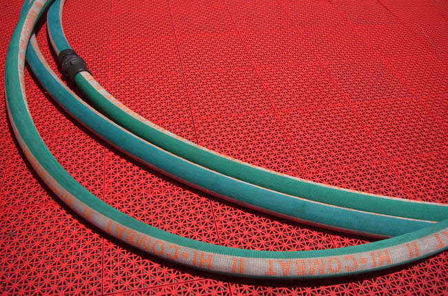 Green hose with orange lettering lies on bright-red mesh flooring