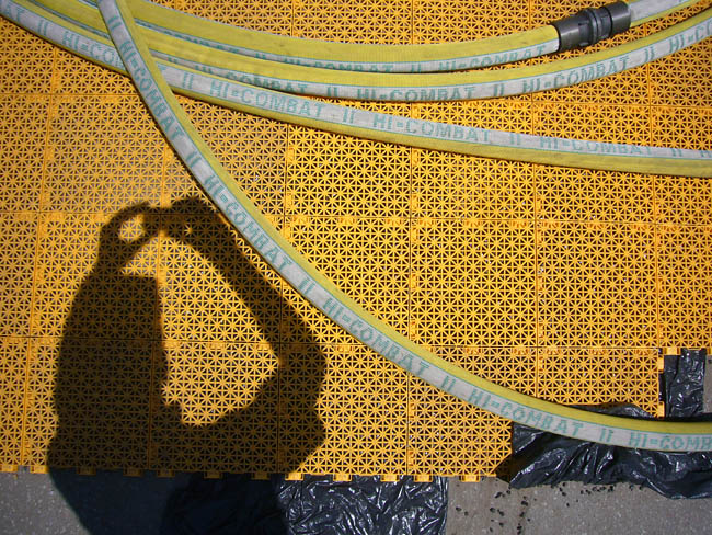 Yellow mesh flooring, yellow hoses labelled HI-COMBAT in green, my shadow as I take the picture