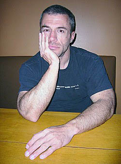 Stephen Cox in black T-shirt, chin resting on one hand