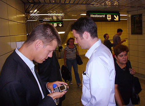 Adam Giambrone stares at BlackBerry in his palm as people stream by on a subway platform