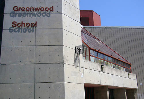Brutalist concrete structure with red accents is labelled Greenwood School in (also red) Helvetica