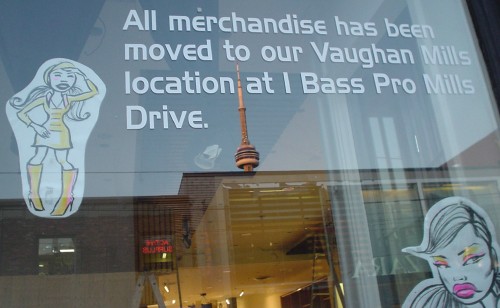 Lettering on shop window in Handel Gothic reads: All merchandise has been moved to our Vaughan Mills location at 1 Bass Pro Mills Drive
