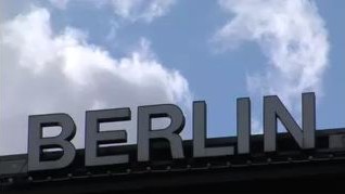 Giant metal letters spell BERLIN atop a building on a partly-cloudy day