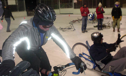 Man in recumbent bike and other man on regular bike, with reflective lines on sleeves and back