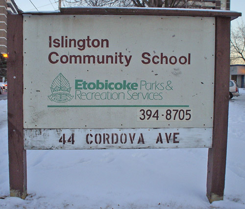 Wooden sign reads ‘Islington Community School’ in hand-drawn Helvetica and ‘Etobicoke Parks & Recreation Services’ in Eras, with other stenciled letters showing an address