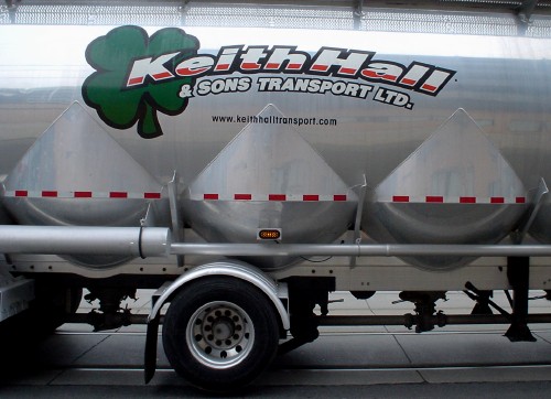 Silver tanker truck with conical protrusions on the sides is labeled Keith Hall & Sons Transport Ltd. in Helvetica, with a four-leaf clover