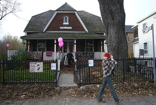 Woman walks by Maple Cottage, decorated with balloons and a few small signs