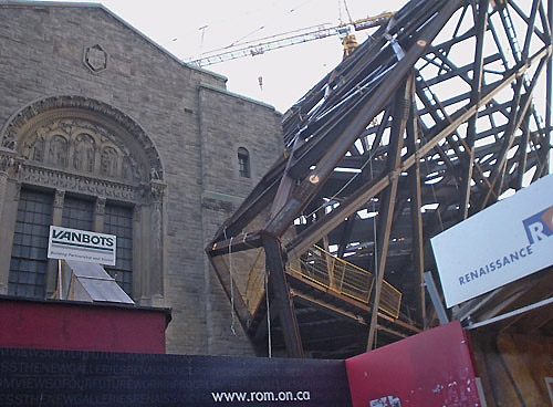 Giant criscrossing metal girders explode like a pyramid off the roof and across the face of an old stone building