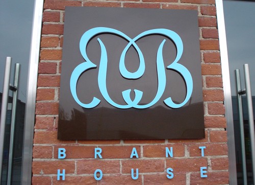 Sign reads Brant House in blue, with twin mirror-image script Bs intertwined in blue on a chocolate-brown background