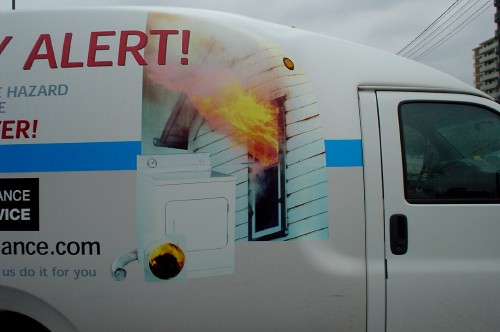 Illustration on side of cube van shows flames shooting from a house window and part of a headline reading ALERT!