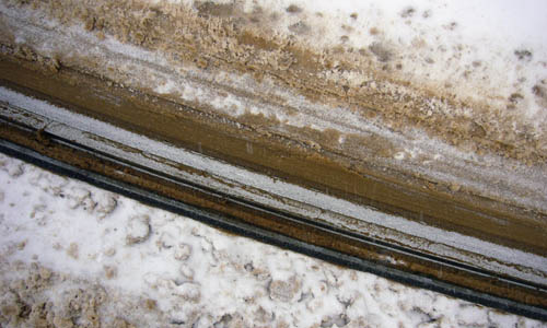 Brown slush stains the snow around a curved streetcar track
