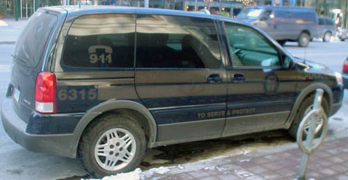 Navy-blue minivan has bronze stripes and markings (6315, 9·1·1, TO SERVE AND PROTECT)