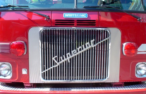 Red White GMC truck has a silver metal grill emblazoned Superior in script