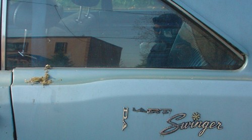 Side of dirty blue coupe shows broken-up Dart Swinger insignia