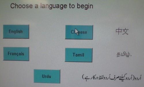 Screen reads “Choose a language to begin’ and lists buttons labeled English and Français (in one column), Chinese and Tamil (another), and Urdu (centred by itself below), with Chinese, Tamil, and Urdu words written alongside the buttons