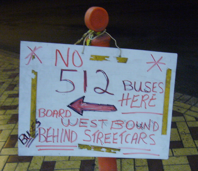 Handwritten sign on pylon reads * NO 512 BUSES HERE * and more