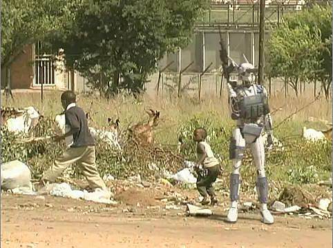 White android in grey bulletproof vest holds a machine gun upright, seemingly guarding two kids and a few head of livestock frolicking behind it