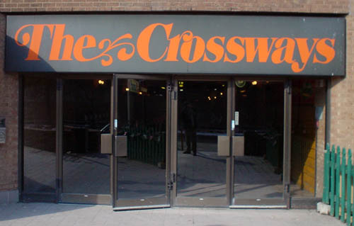 Sign over mall entrance reads The Crossways in bold italic swasy characters (the e extends into plant-like branches)