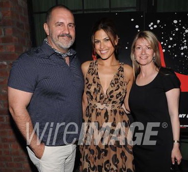 Hugely muscular man with grey beard alongside two starlets