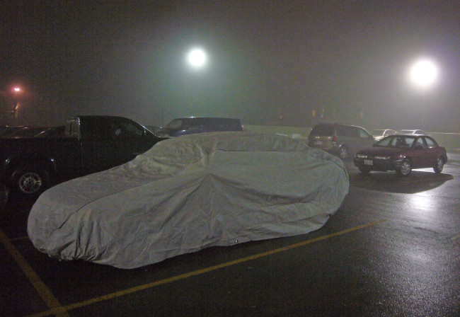 Car under tonneau cover in foggy parking lot