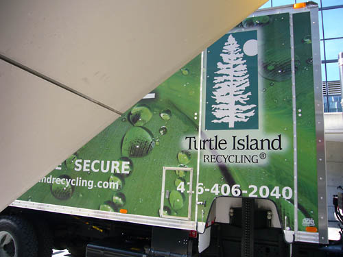 Diagonal panel covers part of the side of a Turtle Island Recycling® truck