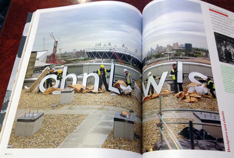 Workmen assembling eight-foot-tall letters spelling John Lewis on pebbled rooftop