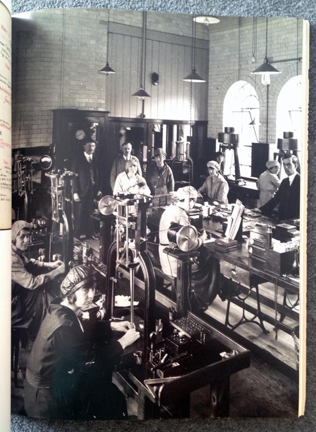 Massive composing room with ladies in hats looking at the camera