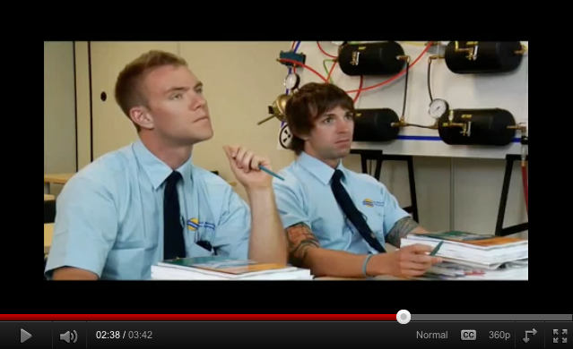 Screenshot: Easton and Horlor in blue short-sleeved BC Transpo shirts and clip-on ties in classroom