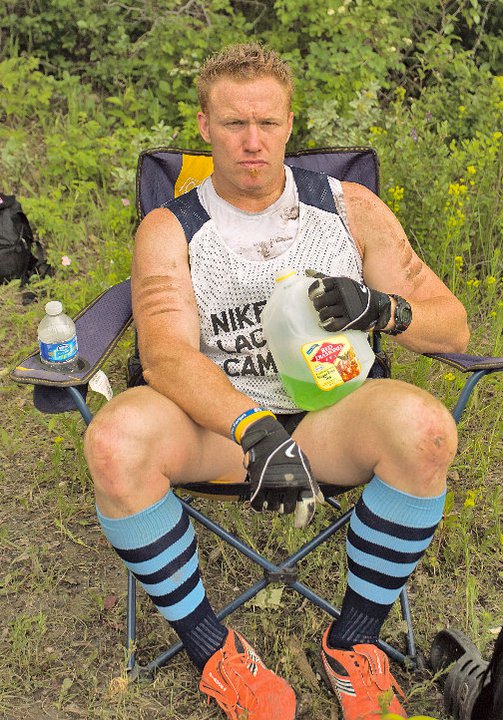 Heath Spence, with black-and-blue striped socks and orange shoes, sits in camp chair