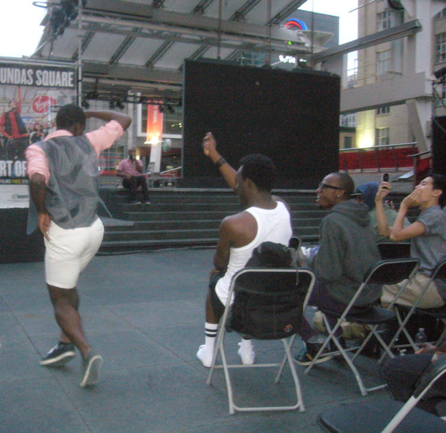 Black guy twirls while other black guy in audience does snaps